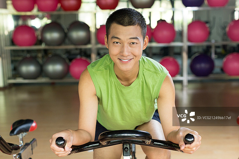 年轻男孩在健身房骑自行车图片素材
