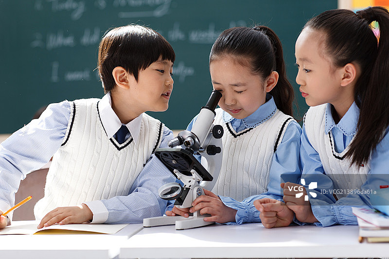 小学生在教室里使用显微镜图片素材