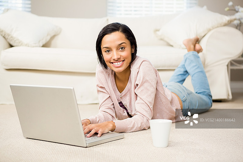 微笑的黑发女人使用笔记本电脑图片素材