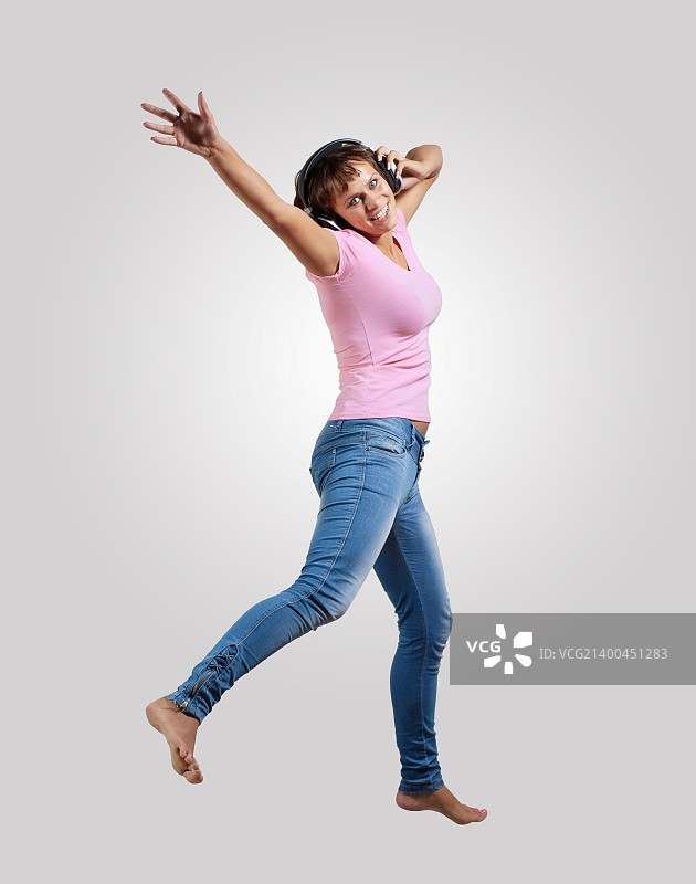 漂亮的现代苗条的嘻哈风格的女人在一个灰色的背景跳舞图片素材