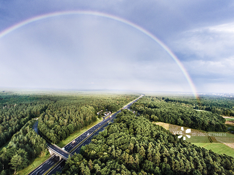公路在绿色的森林里，彩虹在五颜六色的城市里。荷兰图片素材