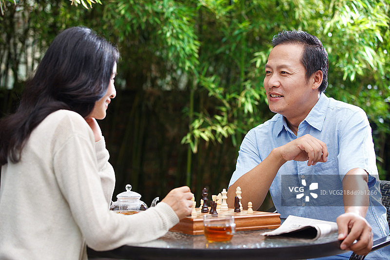 中年夫妇在庭院里下棋图片素材