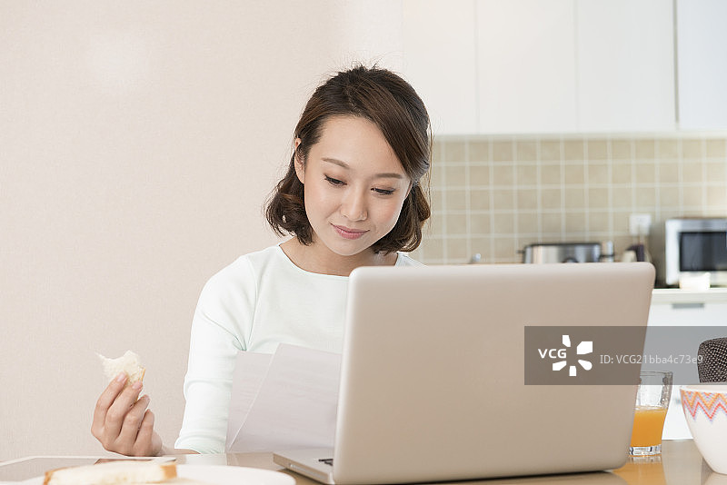 Young woman using laptop at breakfast图片素材