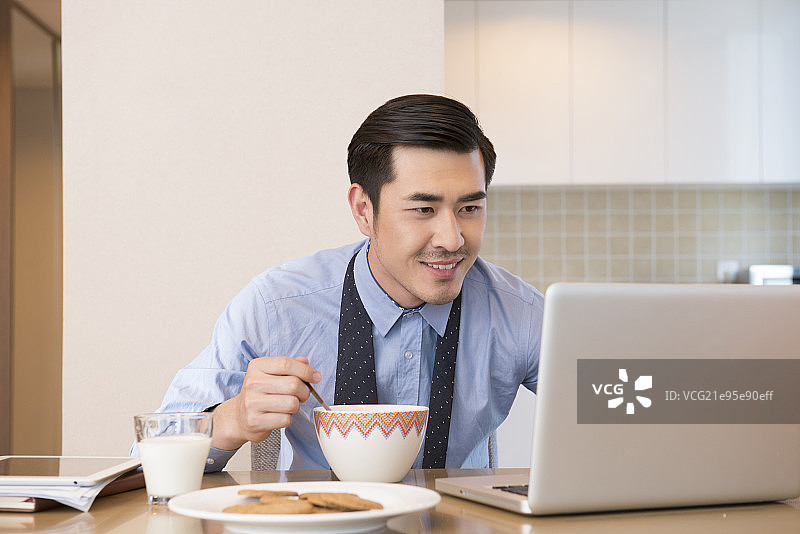 Young man using laptop at breakfast图片素材