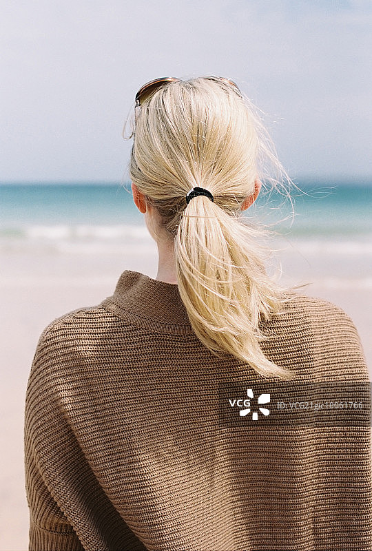 一个金发女人从岸边望着大海。图片素材