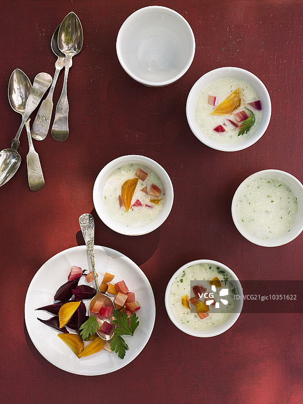 一张桌子上摆着白色的圆形小瓷碗。红色背景下的新鲜食物。图片素材