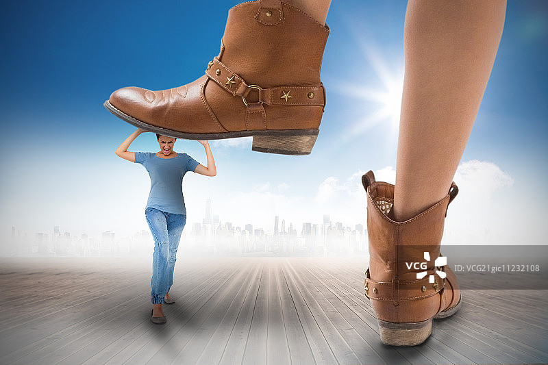 牛仔靴踩在女孩身上的合成图像与地平线上的城市景观相对抗图片素材