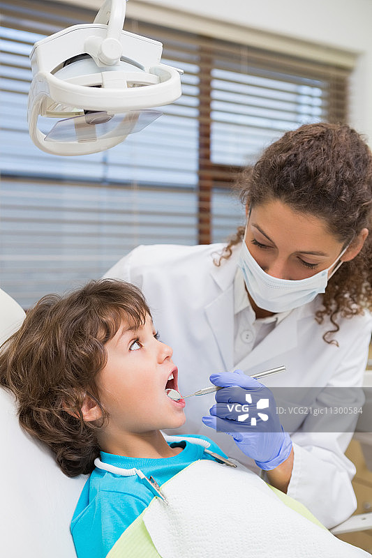 儿科牙医在牙科诊所的牙医椅上检查一个小男孩的牙齿图片素材
