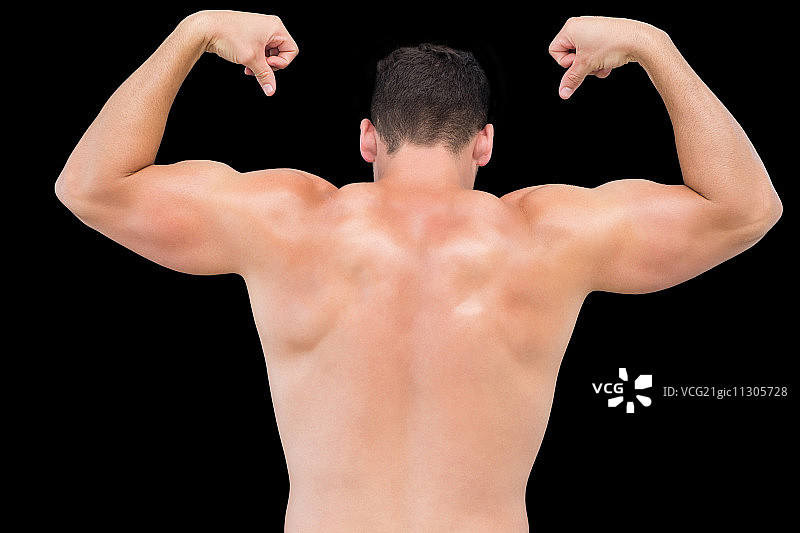 后视图的一个赤膊肌肉男子在黑色的背景上伸缩肌肉图片素材