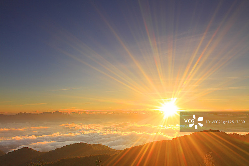 清晨的太阳笼罩在山那边的低云之上图片素材