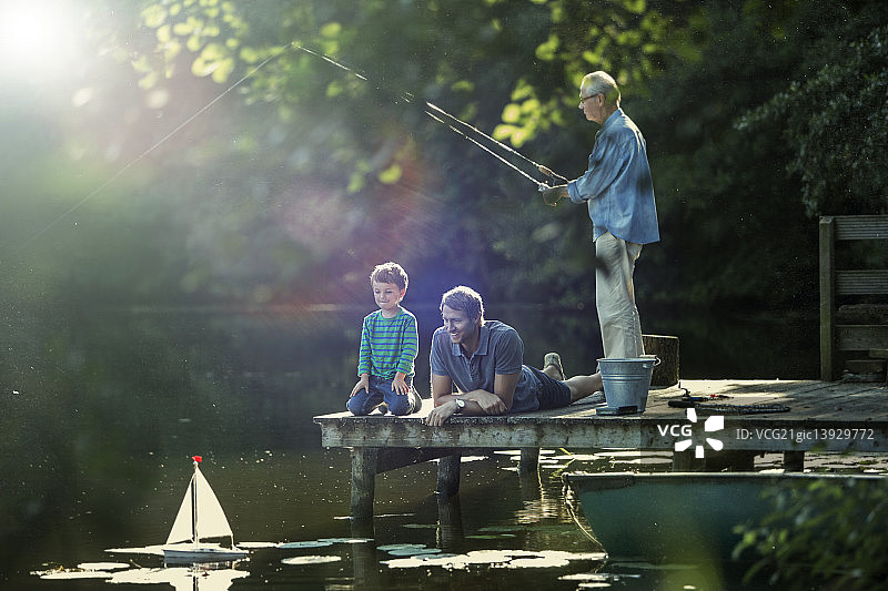小男孩和爸爸、爷爷在湖边钓鱼、玩玩具帆船图片素材