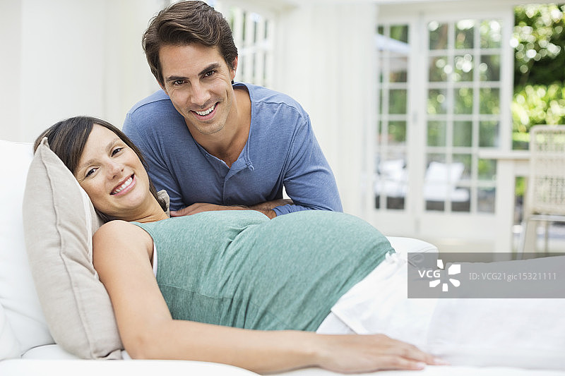 一个男人坐在躺在床上的孕妇旁边图片素材