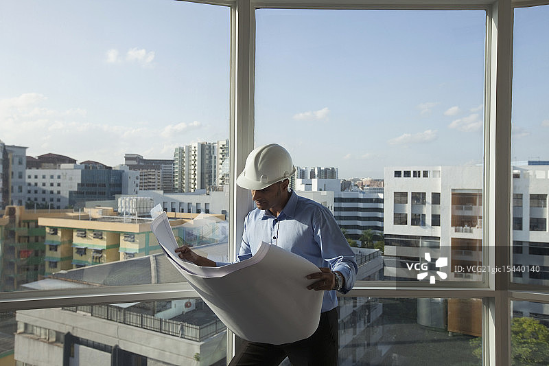 新加坡，男建筑师戴着安全帽看着建筑平面图图片素材