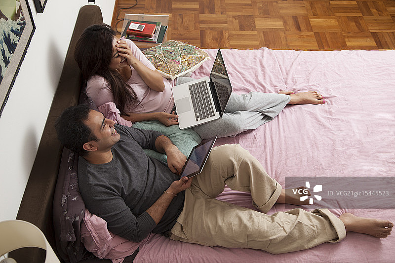 新加坡，一对年轻夫妇在床上笑图片素材