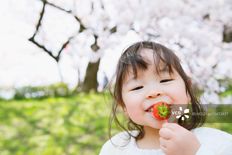 年轻的日本女孩微笑着在城市公园里欣赏樱花图片素材