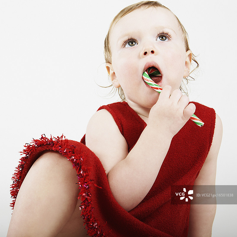 穿着红裙子吃甘蔗糖的女孩图片素材