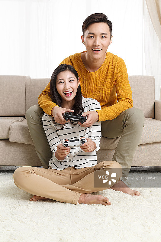 青年情侣坐着沙发上玩游戏图片素材