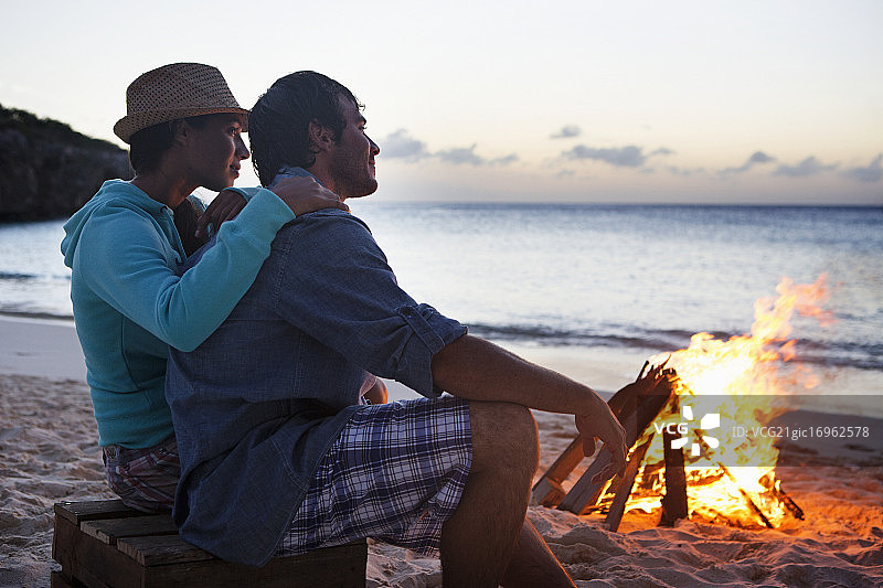 一对夫妇坐在海滩上篝火旁图片素材