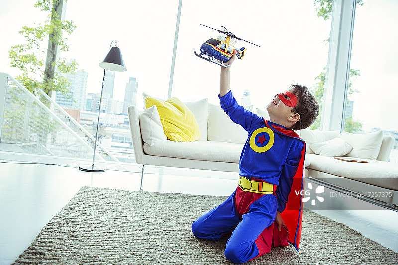 超级英雄男孩在客厅里玩玩具直升机图片素材