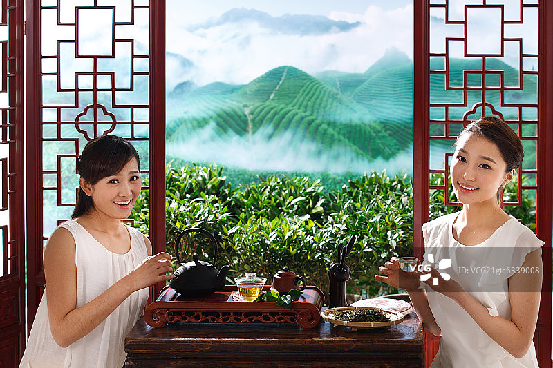 两个东方女孩在茶园的茶舍喝茶图片素材