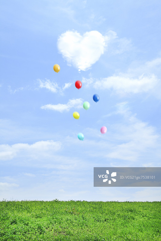 草地和天空中有飞翔的气球和心形的云图片素材