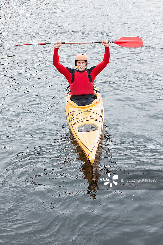 一名快乐的男子在湖中划着皮艇，对着镜头欢呼图片素材