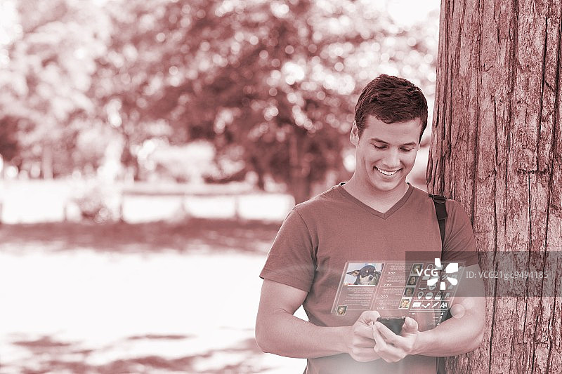 微笑英俊的学生使用他的数字电话在光明公园图片素材