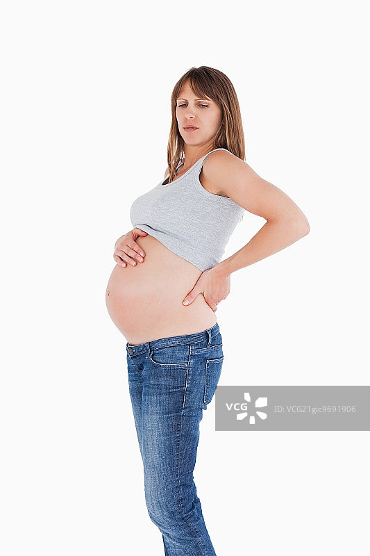 一个漂亮的孕妇拖着她的背站在一个白色的背景图片素材