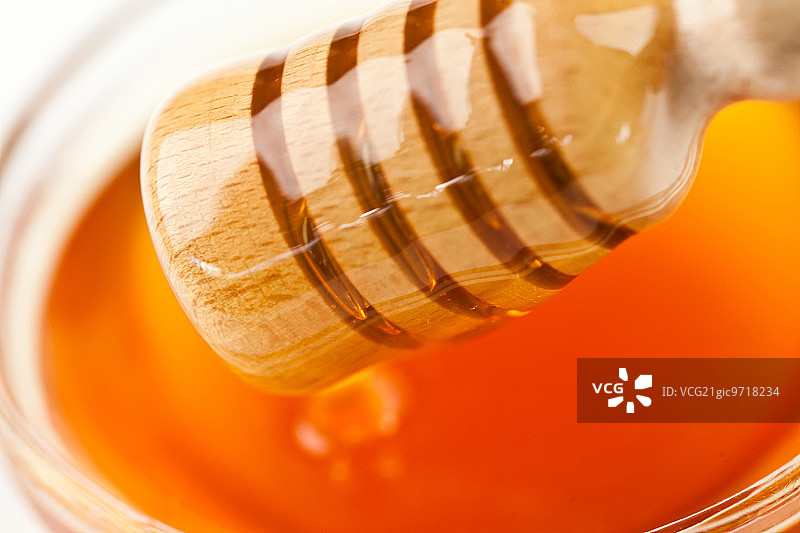蜂蜜舀出一个蜂蜜碗在白色的背景图片素材