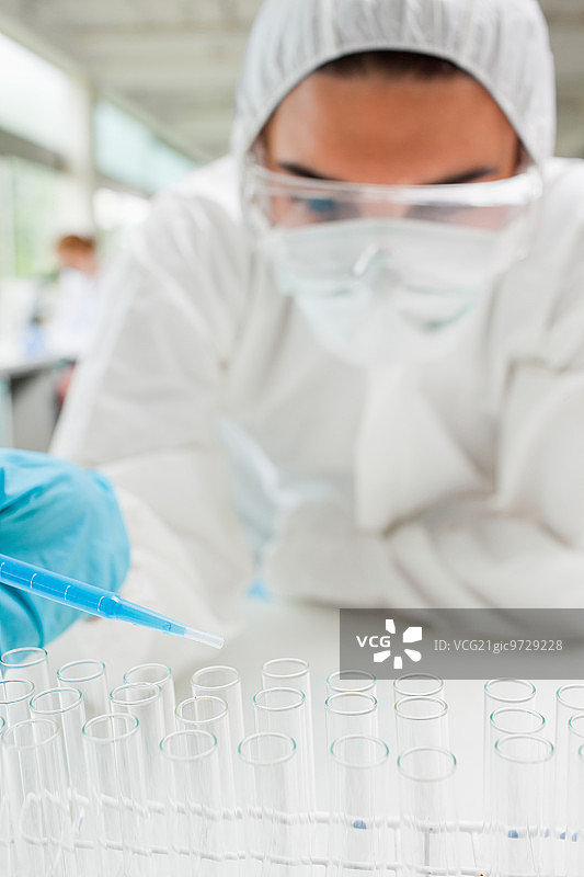 一名受保护的理科女学生在实验室的试管中滴蓝色液体的肖像图片素材