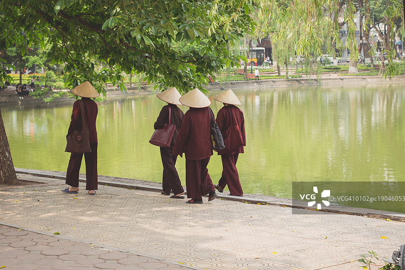 越南河内街头，身着传统服饰、头戴锥形帽子的妇女图片素材