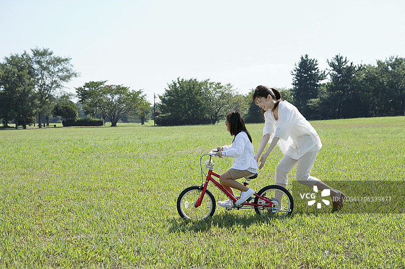 在公园练习骑自行车的家长和孩子图片素材