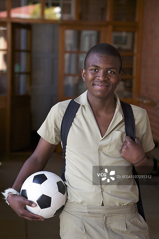 南非夸祖鲁-纳塔尔省的走廊里，一个男孩拿着一个足球的肖像图片素材