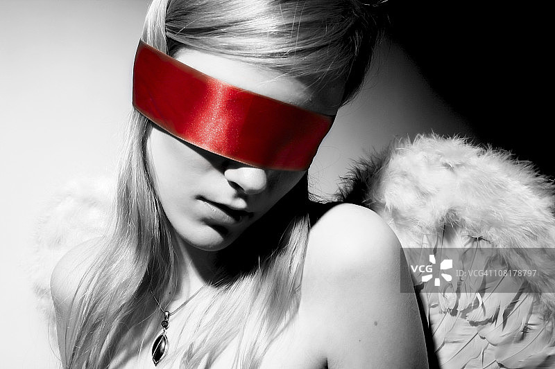 黑白相间的女天使用红丝带蒙上眼罩图片素材