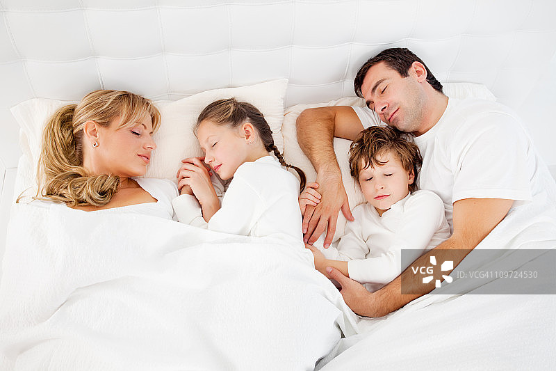 可爱的一家人睡在一起，躺在床上图片素材