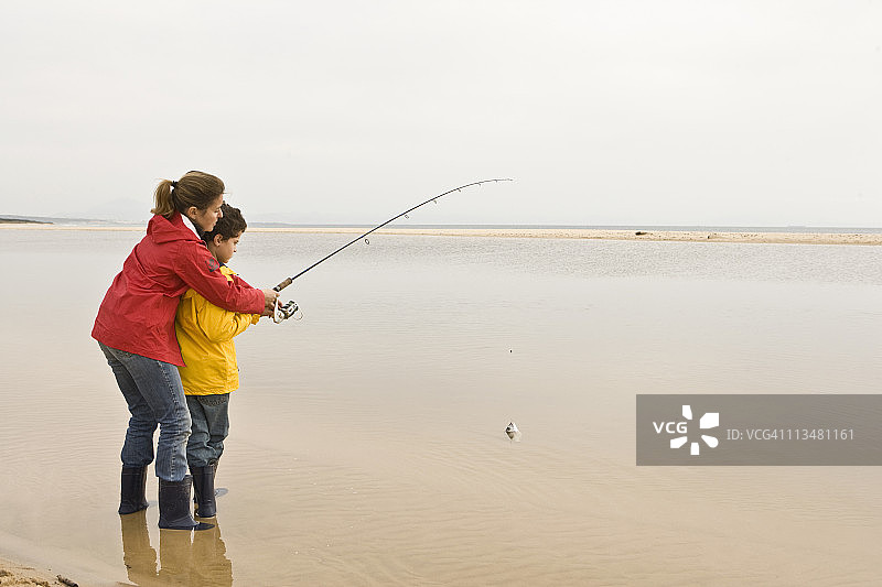 母亲在海滩教儿子钓鱼图片素材