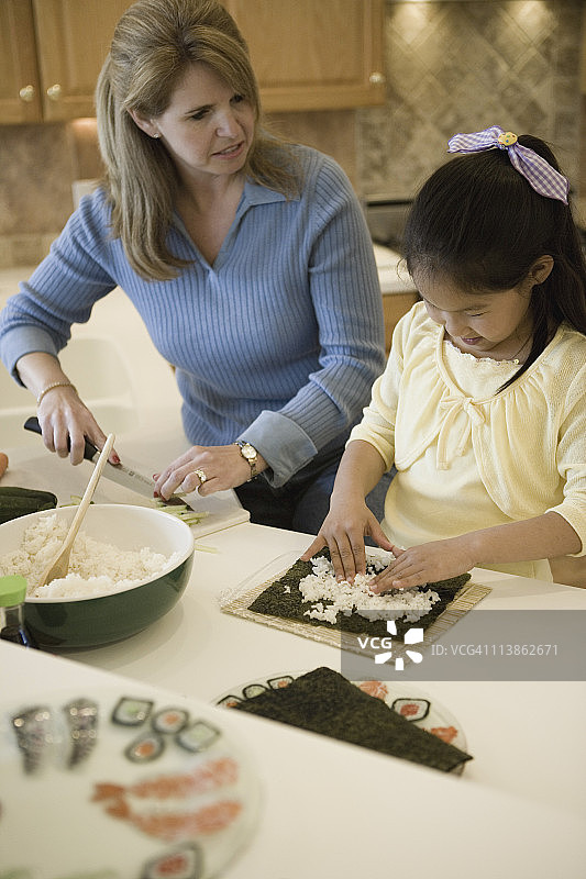 女人和女儿在厨房做寿司图片素材