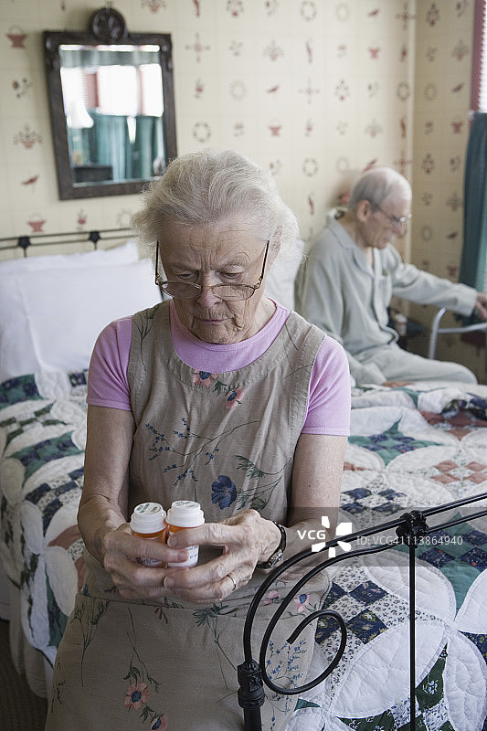 老女人坐在床上看处方瓶图片素材