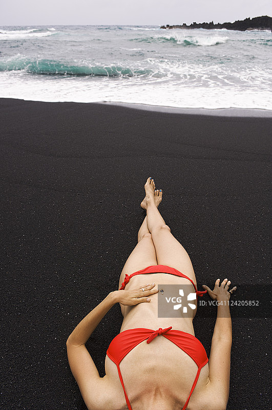 在黑色沙滩上晒太阳的女人图片素材