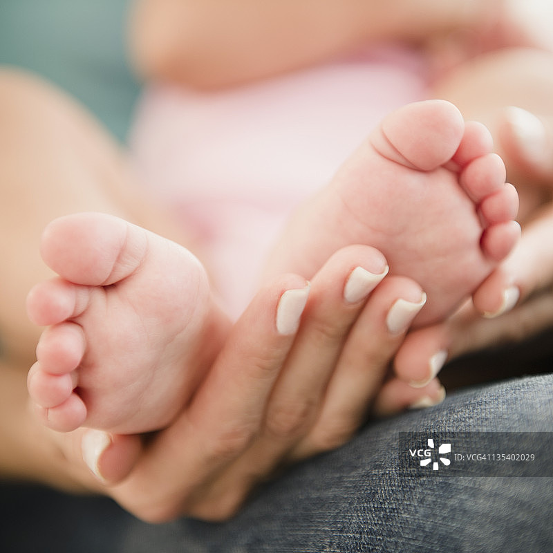 母亲双手抱着婴儿的脚图片素材