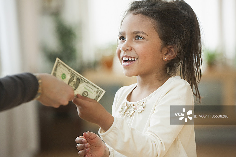 母亲递给女孩一美元的钞票图片素材