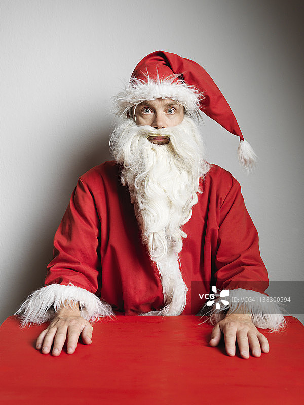 一个穿着圣诞老人服装的男人坐在桌旁图片素材