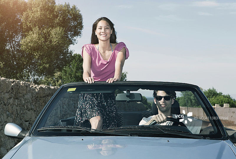 西班牙，马略卡岛，一个年轻人开车，一个女人站在敞篷车里图片素材