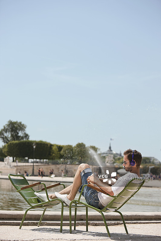 法国巴黎，法兰西岛，杜伊勒里宫花园，一个坐在椅子上看杂志的人图片素材