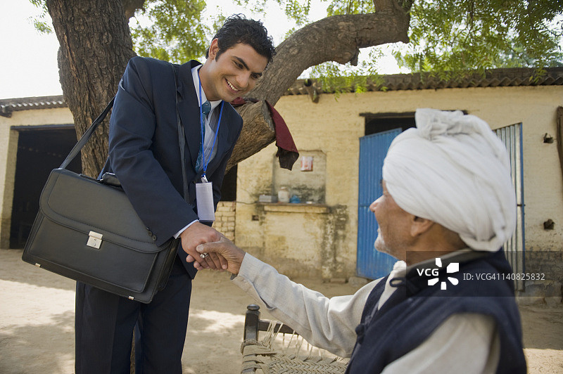 印度哈里亚纳邦哈森普尔，金融顾问与一位农民握手图片素材