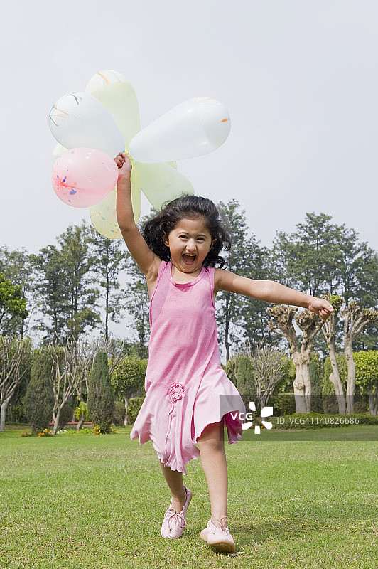 女孩在公园里拿着气球跑图片素材