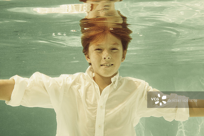 穿着衬衫的男孩在游泳池里游泳图片素材