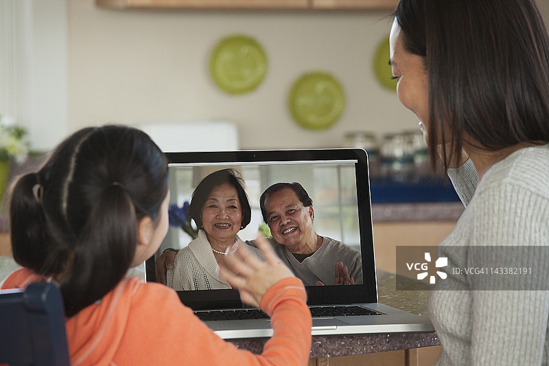 亚洲母女在电脑上和家人聊天图片素材