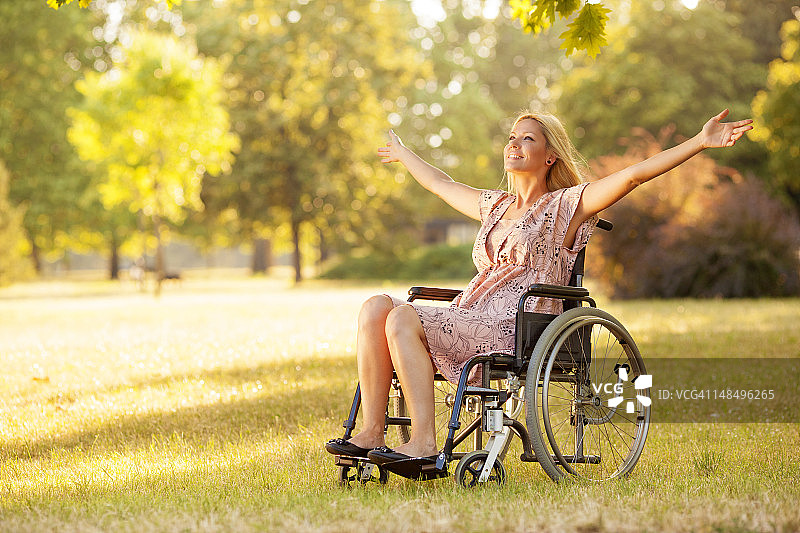 坐在轮椅上的残疾年轻女子享受户外活动。图片素材