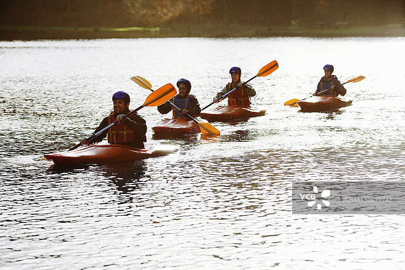 皮划艇运动员一起在平静的湖面上划船图片素材